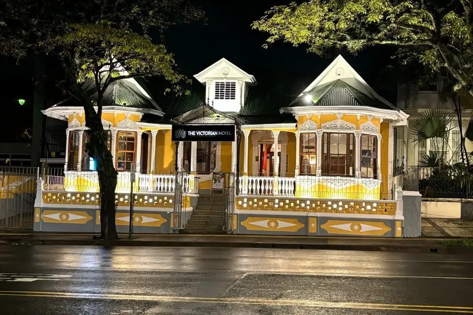 The Victorian Hotel's yellow-and-white 1910 facade lit at night on Paseo Colón